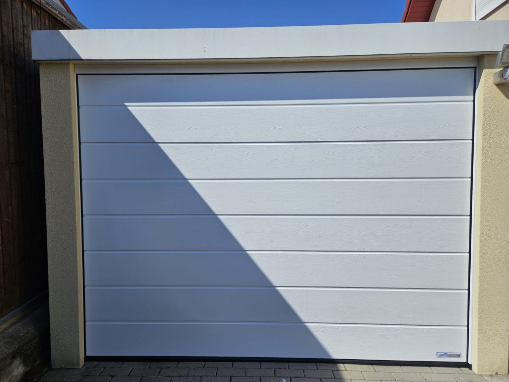 Fertiggarage mit verkehrsweißem Sektionaltor modernisiert